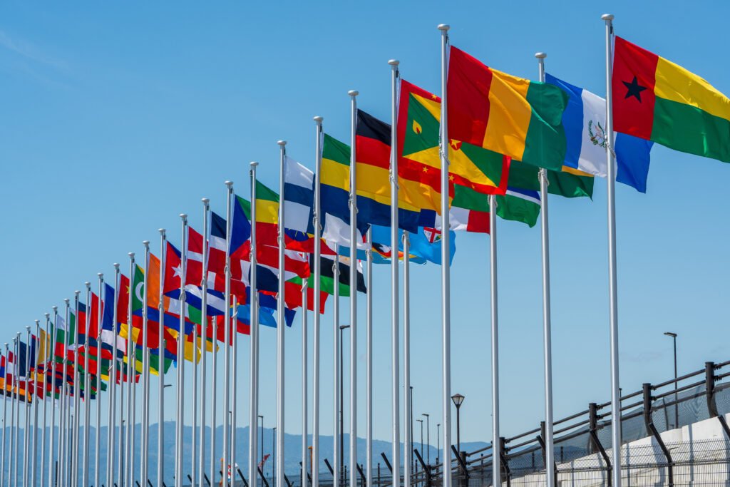 international flags flying high against clear sky at the yumeshima, an artificial island in osaka bay.
